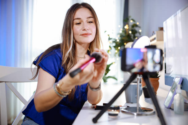 istock Young women using social media shoots makeup video in her room 2195924540