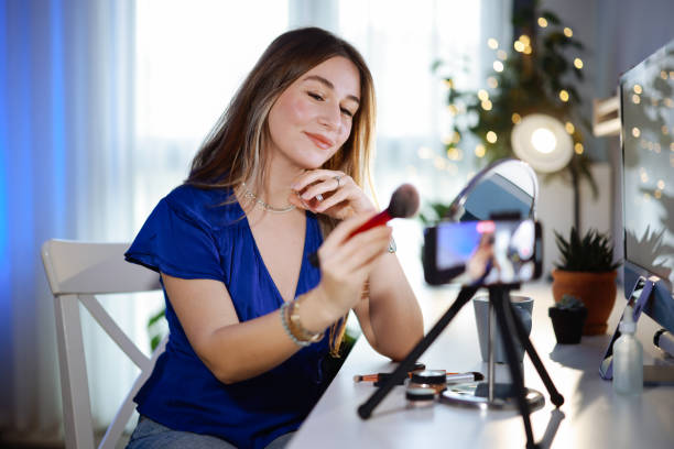 istock Young women using social media shoots makeup video in her room 2195924612