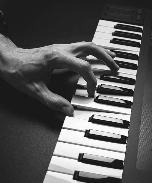 istock A midi keyboard with a man's hand playing it, piano keys. 2195926383