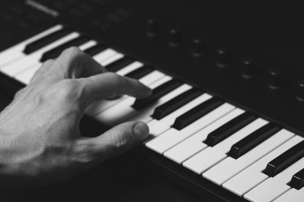 istock A midi keyboard with a man's hand playing it, piano keys. 2195926385