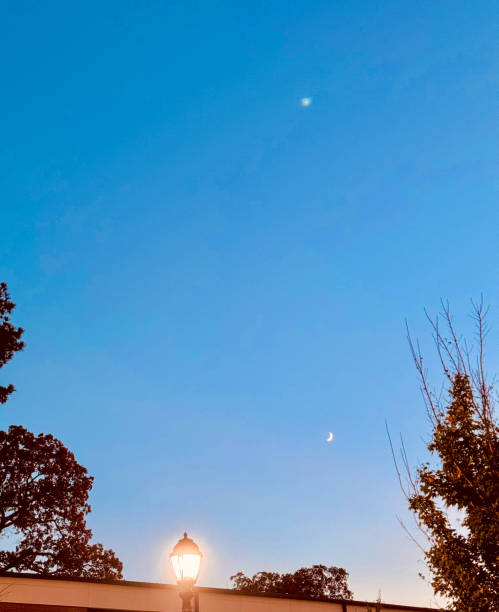 istock Sunset Above Building With Lamp Post And Moon 2195927589