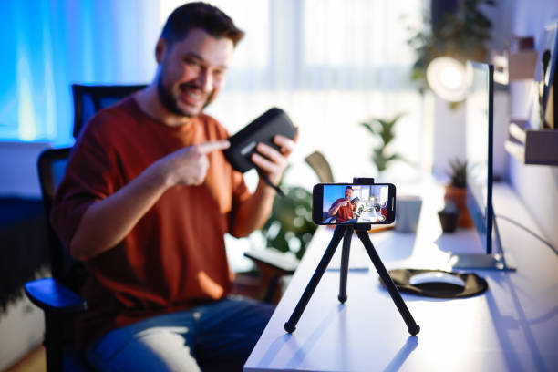 istock Male blogger unboxing parcel with tech product using smartphone on tripod, recording video content for tech blog at home 2195928203