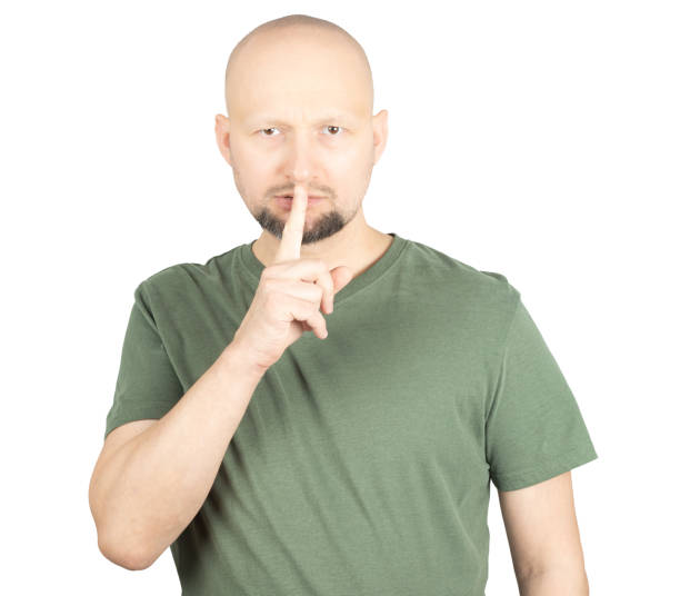 istock Serious man making a silence gesture by placing finger on lips 2195928560
