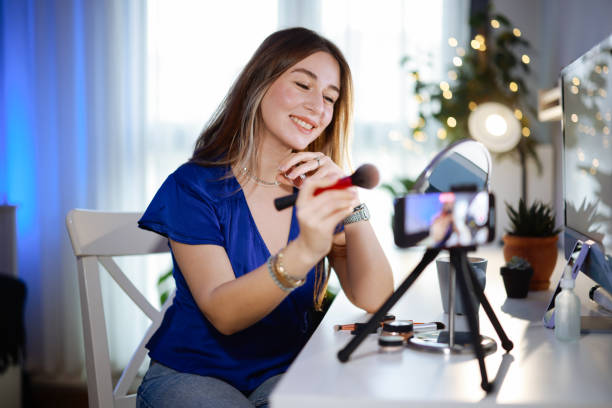 Young women using social media shoots makeup video in her room stock photo