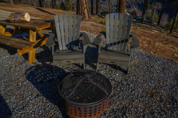 istock Adirondack Chairs and Fire Pit on Gravel with a Wooden Picnic Table in a Forest Setting 2195931345