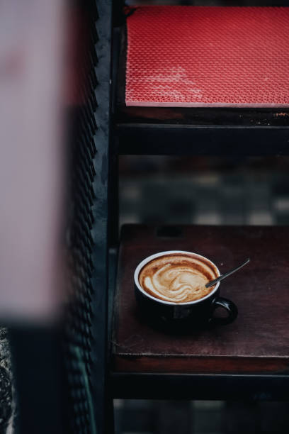 istock Cappuccino in a black ceramic mug on a wooden table side view 2195932067