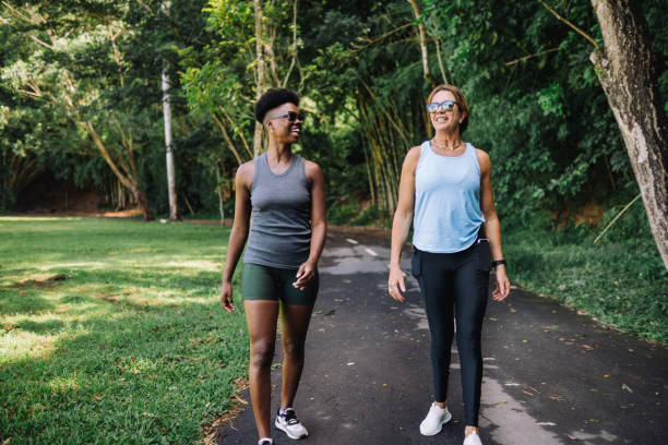 Two women walking on a cool shady public park path