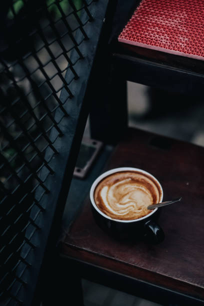 istock Cappuccino in a black ceramic mug on a wooden table side view 2195932104