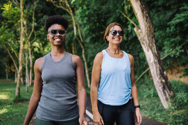 istock Two happy women walking on a path surrounded by lush forest 2195932114
