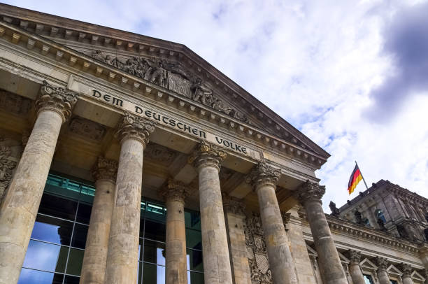Berlin, Germany - 03. October 2024: Low angle view of Reichstag building facade with german flag waving in Berlin, Germany