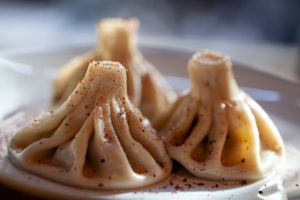 Traditional khinkali dumplings sprinkled with spices on a white plate and softly lit