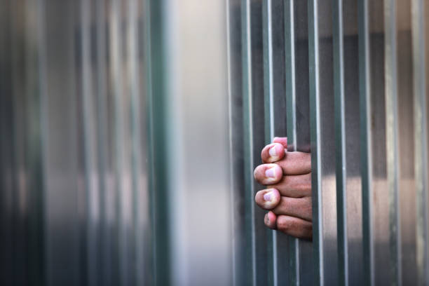 istock Hand Holding Metal Bars in a Prison or Jail Environment 2195941728