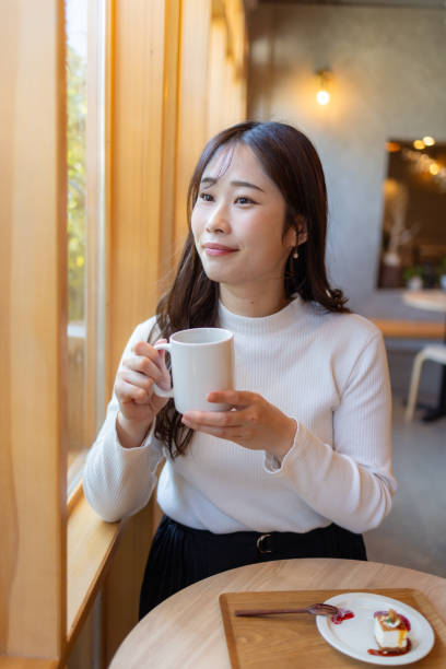 istock Female tourist looking at view through window in cafe 2195944060