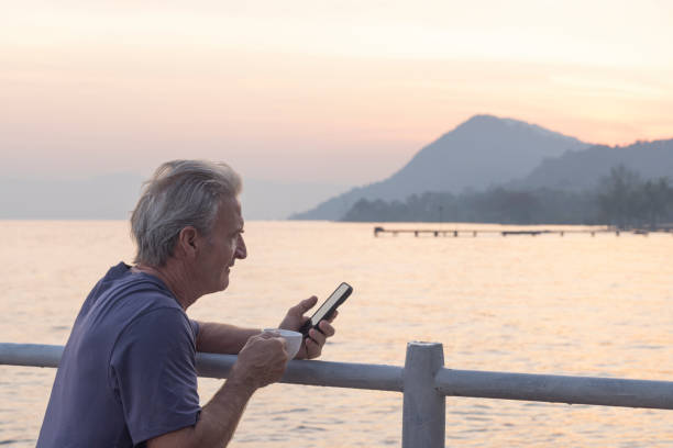 istock Mature man leans on railing above sea at sunrise 2195944430