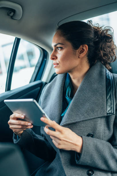 istock Woman using digital tablet on the back seat of a car 2195952223