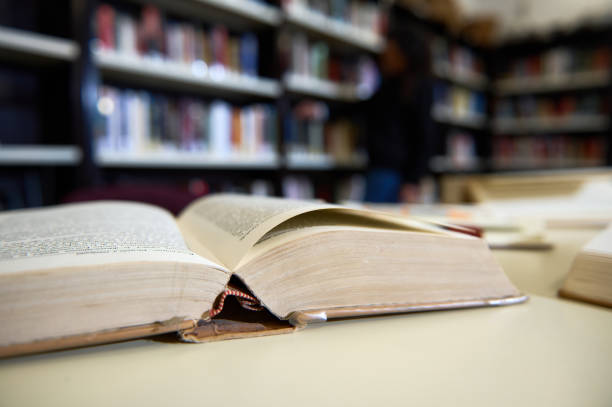 istock Open Book in Library With Shelves Blurred in Background 2195952955