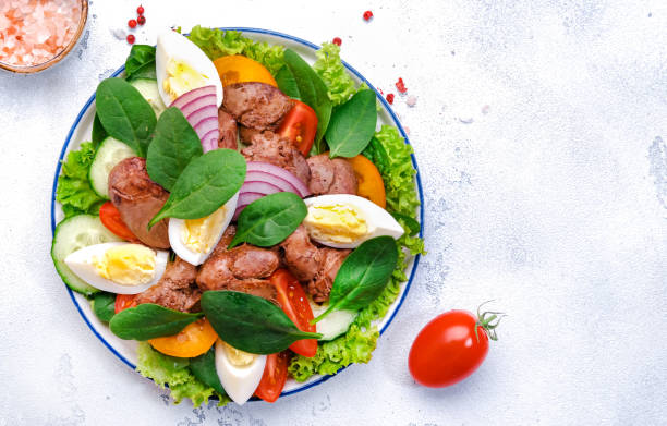 istock Perigord salad with chicken liver, tomatoes, cucumbers, eggs, lettuce and spinach. White background, top view 2195965651