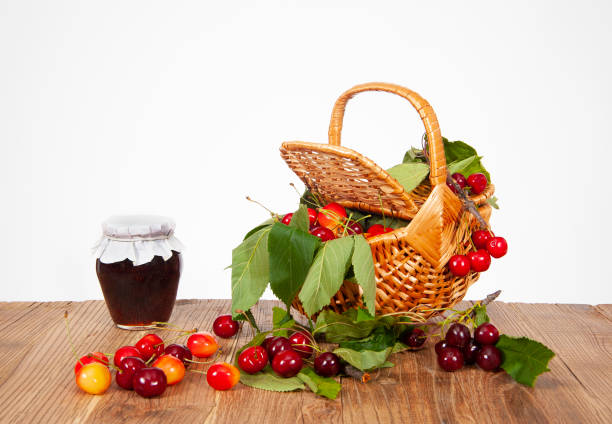 Still life, wicker basket, jar and jam, fresh cherries on the table