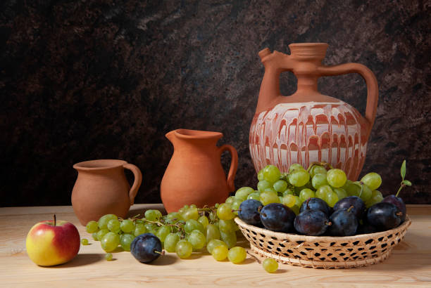 Still life, ceramic dishes, wicker basket and various fruits on the table