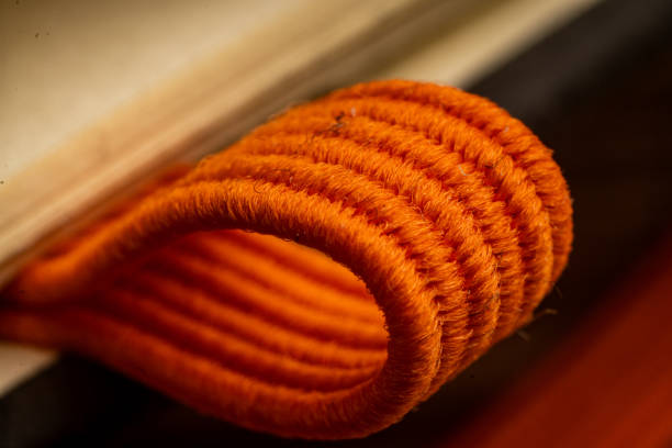 Close-up view of the vibrant orange spiral binding on a notebook located in an office environment. This detail showcases the texture and color against a backdrop of paper and stationery.