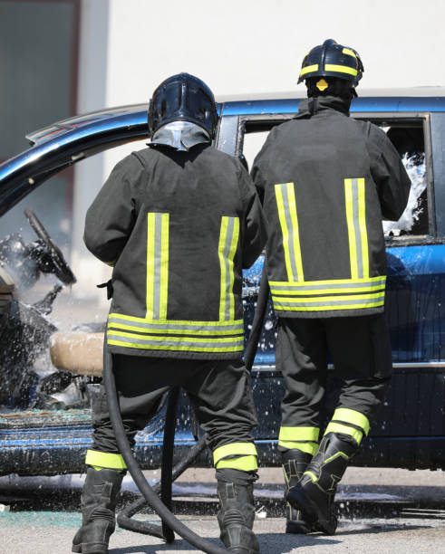 istock two firefighters extinguishing the fire of a crashed car after a road accident 2195980120