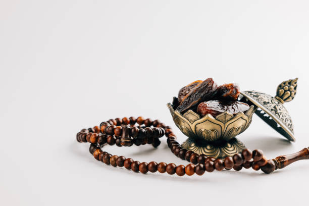 istock Holy Ramadan celebration with dates in ornate dish and prayer beads on a simple white background 2195982339