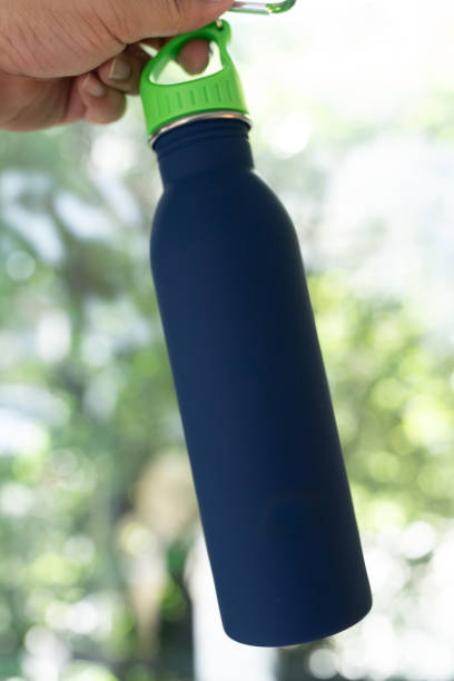istock Blue water bottle with green lid held in a hand. 2195986504