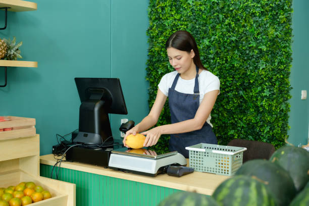 istock Female entrepreneur carefully weighing tropical fruits while using digital tools at her fruit store. Reflecting quality control, focus, and professionalism in her business. 2195988194