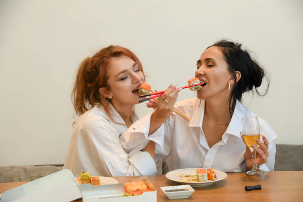 istock Friends enjoying sushi together while playfully feeding each other in a cozy setting, capturing a moment of joy and friendship 2195988276
