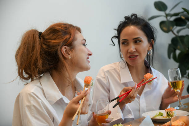 istock Friends enjoying sushi and drinks in a vibrant setting while sharing laughs and good times with each other during a cozy gathering 2195988288