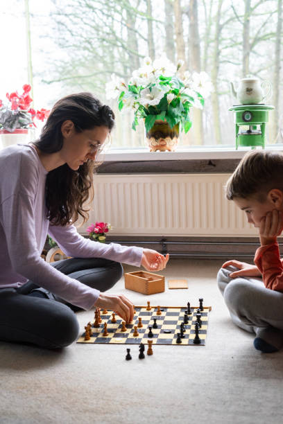 istock Mother and son concentrating while playing chess at home 2195988831