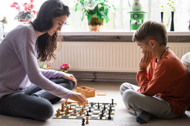 istock Young woman and child playing chess at home 2195988832
