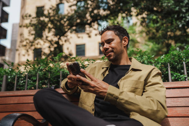 istock Stylish man on a park bench, immersed in his smartphone 2195989026