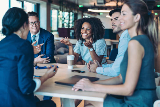 istock Group of business people sitting around a table and talking 2195989515