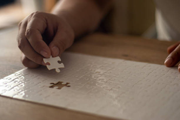 istock A man's hand is putting together a jigsaw puzzle. 2195991225