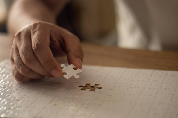 istock A man's hand is putting together a jigsaw puzzle. 2195991274