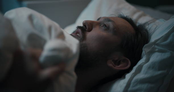 istock Young man lying in hospital bed, covered with a blanket, staring upwards, battling health issues 2195991745