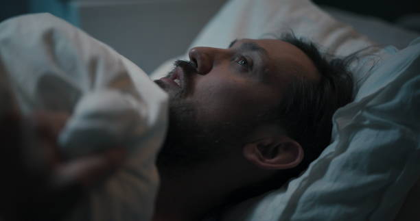 istock Young man lying in hospital bed, covered with a blanket, staring upwards, battling health issues 2195991750
