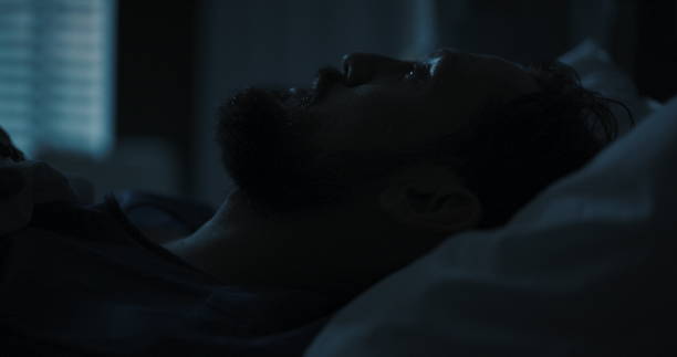 istock Young man lays in a hospital bed, his gaze fixed on the ceiling, lost in thought 2195992004