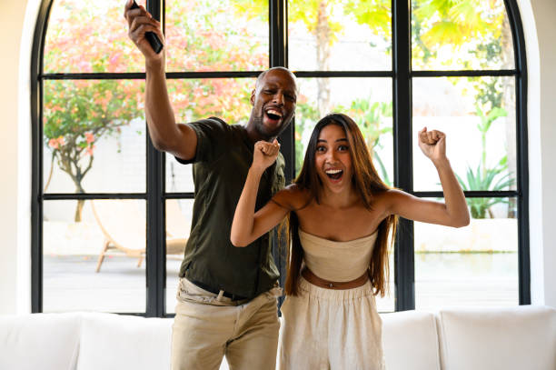 istock Excited couple celebrating success while watching TV indoors 2195996394