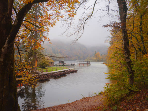 Stunning morning view of lake with boats in Plitvice National Park. Colorful autumn foggy scene of Croatia, Europe. Beauty of nature concept background.
