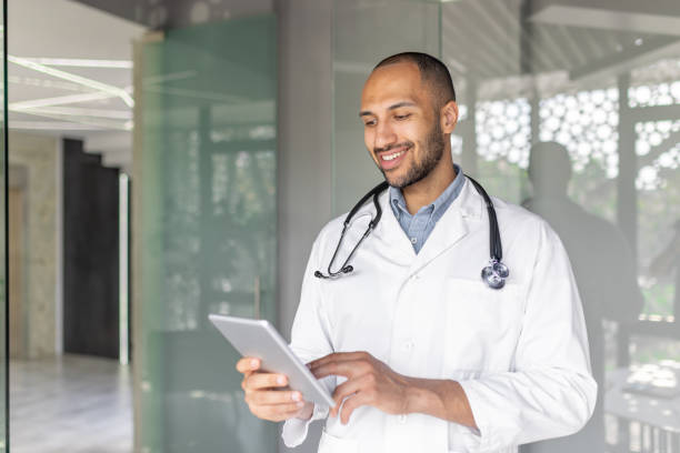 istock Smiling doctor checking information on a tablet in a modern office 2195997761
