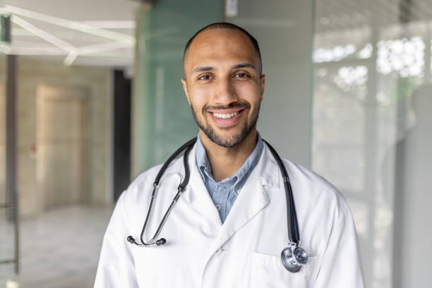 istock Confident professional doctor smiling at a clinic wearing a white coat and stethoscope 2195997770