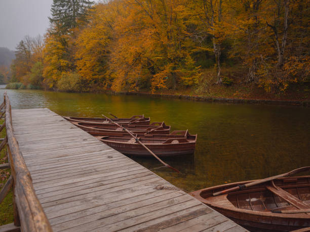 Stunning morning view of lake with boats in Plitvice National Park. Colorful autumn foggy scene of Croatia, Europe. Beauty of nature concept background.