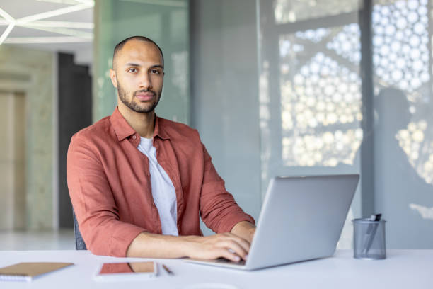 istock Man working at a desk with a laptop in a bright office setting 2195999741