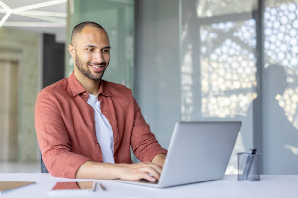 istock Man working on laptop and smiling in a modern office workspace 2195999750