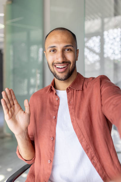 istock Smiling man waving during a video call in a modern indoor setting 2196000177