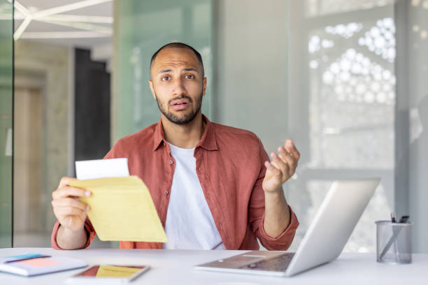istock Confused office worker holding an envelope in a modern office space 2196000187