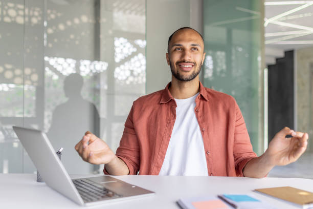 istock Smiling man meditating during a work break at a modern office desk 2196000208