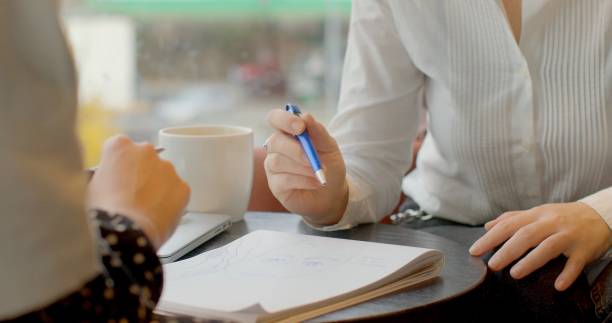 istock Hands meet over notes in a cozy coffee shop, fostering collaboration 2196000582